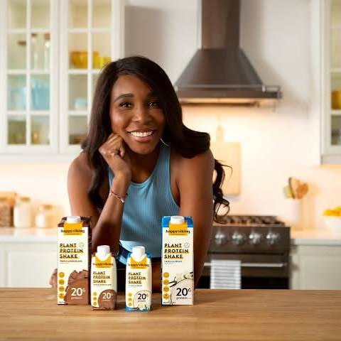 Venus Williams leaning on a kitchen counter behind a lineup of Happy Viking protein packets